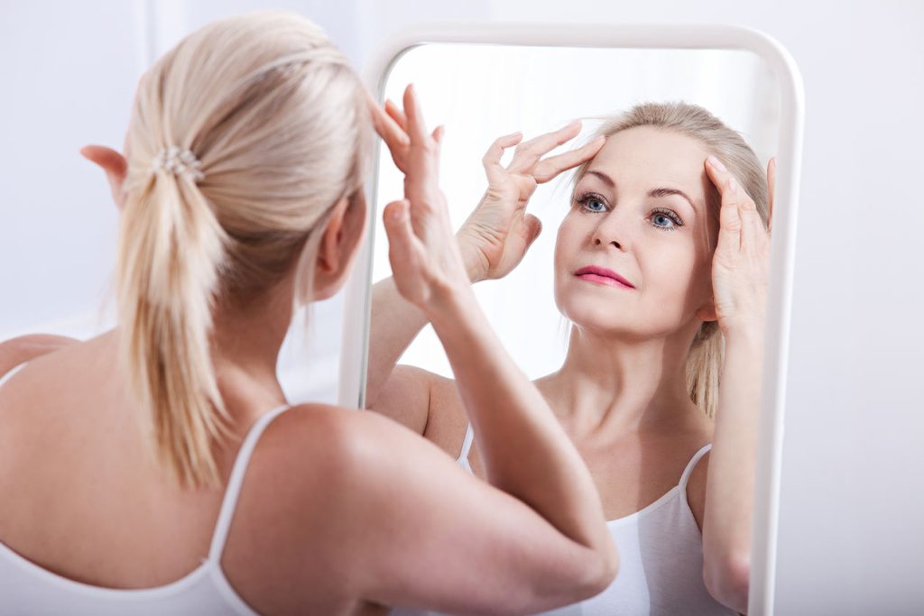 Woman admiring her face with firm wrinkly free skin. Botox Alexus MD.